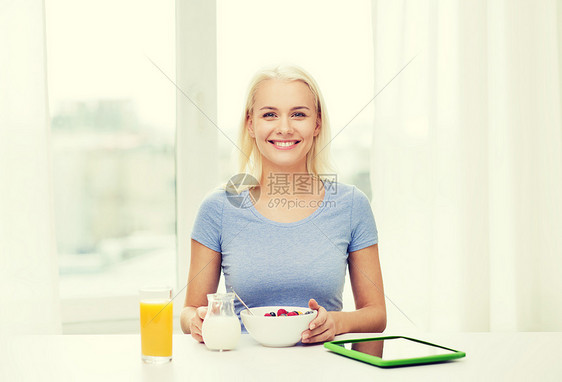 健康的饮食,饮食人的微笑的轻妇女与平板电脑家里吃早餐图片