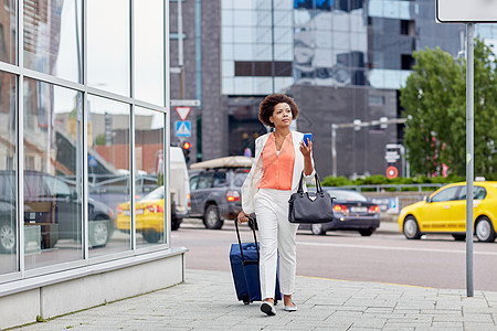 旅行,商务旅行,人技术轻的非裔美国妇女带着旅行袋智能手机城市街道图片