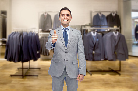 商业,人,男装,销售服装快乐的微笑商人穿着西装,服装店的背景上竖大拇指图片