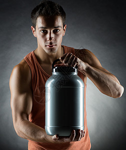 运动,健美,力量人的轻人站着着灰色背景上的蛋白质罐子图片