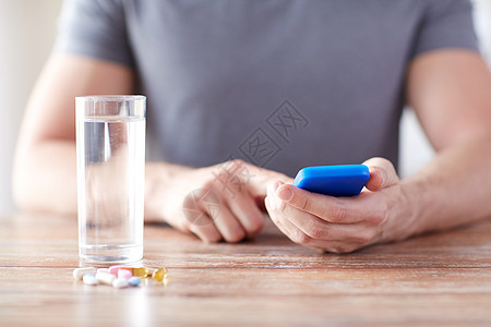 药物,技术,营养补充剂人的男手智能手机,药丸水桌子上图片