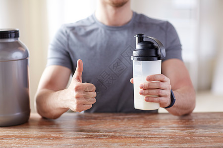 运动,健身,健康的生活方式人们的近距离的人健身手镯与蛋白质瓶大拇指图片