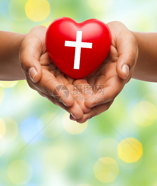 宗教基督教慈善绿色灯光背景下,女手握红心,带基督教十字符号图片