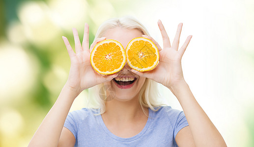 健康饮食,机食品,水果饮食,漫画人的快乐的女人玩得开心,用橙色的切片覆盖她的眼睛绿色的自然背景图片
