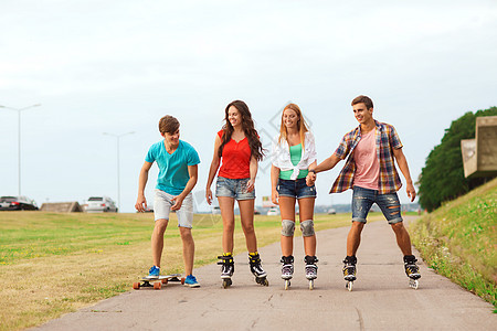 假期,爱友谊的群微笑的青少带着溜冰鞋滑板户外骑马图片