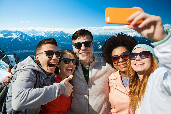 人,旅游,友谊技术群快乐的十几岁的朋友用智能手机自拍,奥地利背景的阿尔卑斯山上竖大拇指图片