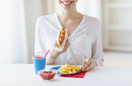 食物主义快乐的女人吃热狗炸薯条与饮料纸杯图片