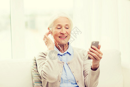 技术,龄人的快乐的老妇女与智能手机耳机家里听音乐图片