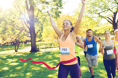 健身,运动,胜利,成功健康的生活方式快乐的女人赢得比赛,并率先完成红色丝带超过运动员跑马拉松与章号码户外图片