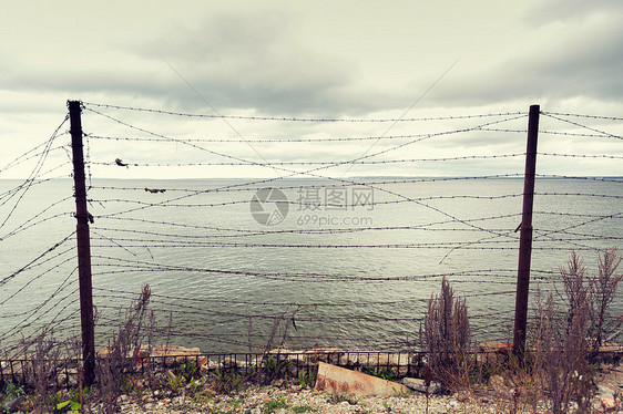 监禁,限制灰色的天空海洋上的铁丝网图片