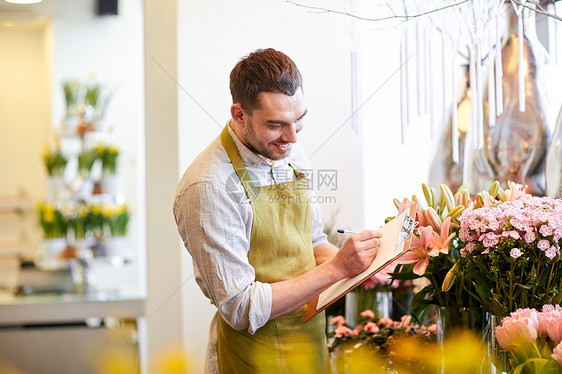 人,销售,零售,商业花卉快乐微笑的花店男子与剪贴板写作笔记订单花店图片