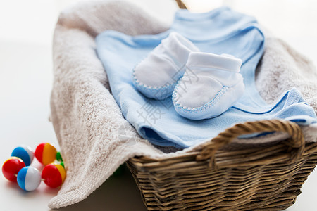 服装,婴儿,母亲象白色婴儿靴与堆衣服,毛巾拨浪鼓为新生男孩篮子图片