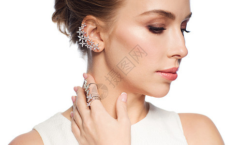 豪华,婚礼人的微笑的女人穿着白色连衣裙,戴着白色背景的钻石珠宝专注于耳环手指上的戒指图片