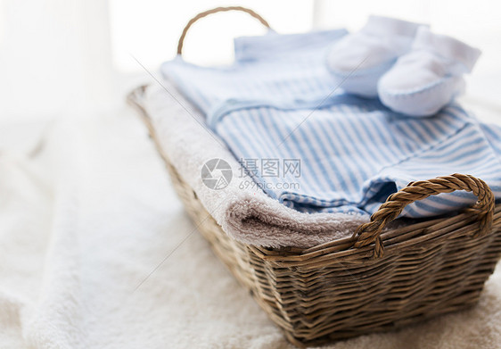 服装,婴儿,母亲象白色婴儿靴与堆衣服毛巾为新生男孩篮子桌子上图片