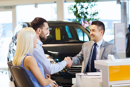 汽车业务,汽车销售,人们的愉快的夫妇与经销商握手车展沙龙图片