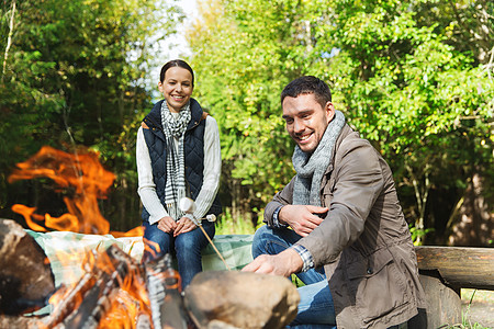 野营,旅行,旅游,徒步旅行人们的快乐的夫妇烤棉花糖超过营火树林里图片