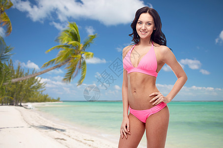 人们,暑假,旅游旅游快乐的轻女人穿着粉红色比基尼泳衣异国情调的热带海滩与棕榈树背景,图片