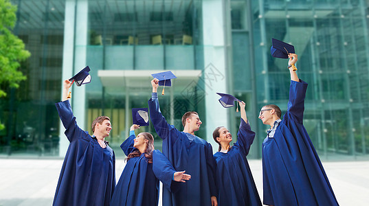 教育毕业人的群微笑的学生穿着长袍,学校大学建筑背景上挥舞着黑板图片