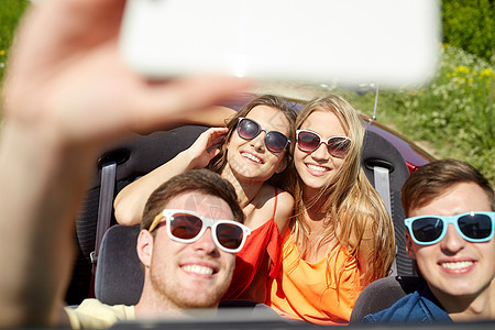 休闲,公路旅行,旅行人们的快乐的朋友驾驶敞篷车,智能手机户外自拍图片