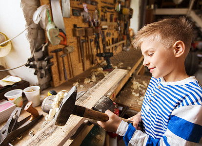 木工,建筑人的快乐的小男孩用锤击木板车间图片