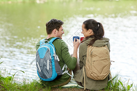 旅行,旅游,徒步旅行,野营人们的幸福的夫妇与杯子喝茶大自然的河岸图片