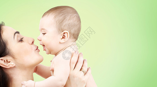 家庭,母亲,养育,人儿童保育的快乐的母亲亲吻可爱的婴儿绿色的背景图片