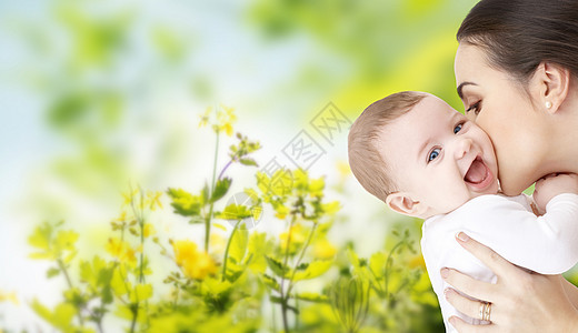 家庭,母亲,养育,人儿童保育的快乐的母亲亲吻可爱的婴儿绿色的自然背景图片