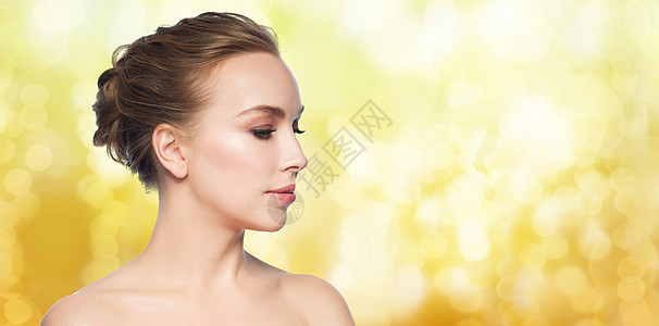 美丽的年轻女性在黄色假日灯光背景下图片
