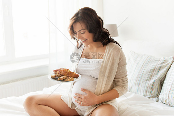 怀孕,健康的饮食,食物人们的快乐的孕妇家里吃羊角包图片