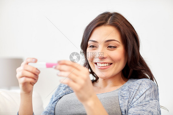 怀孕,生育,生育人的快乐的微笑女人看着怀孕测试家里图片