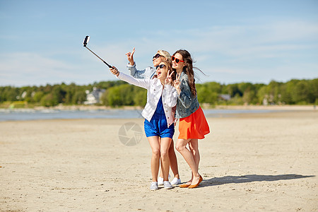 厦门海滩暑假,假期,旅行,技术人的群微笑的轻女海滩上自拍杆上用智能手机拍照背景