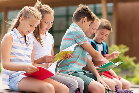 小学教育,友谊,童,沟通人的群快乐的小学生笔记本坐户外长凳上图片