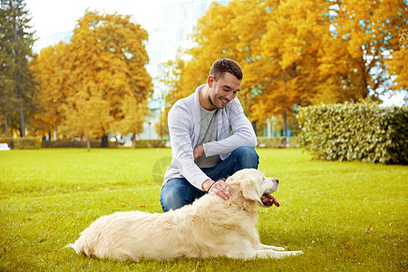 家庭,宠物,动物人的快乐的人与拉布拉多猎犬秋天的城市公园散步图片