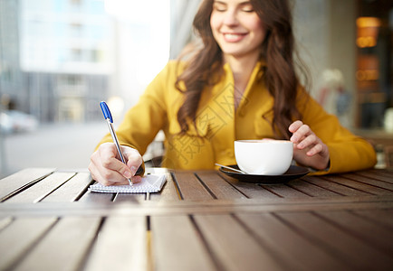 休闲人的快乐的轻妇女十几岁的女孩喝杯卡布西诺,并写信笔记本城市街道咖啡馆露台咖啡馆里带着笔记本卡布奇诺的图片