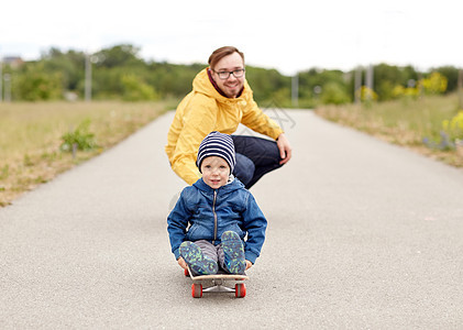 家庭,童,父亲,休闲人的快乐的父亲小儿子骑滑板图片