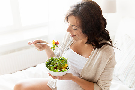 怀孕,健康的食物人们的快乐的孕妇家吃蔬菜沙拉图片
