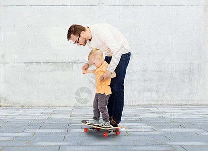家庭,童,父爱,休闲人的快乐的父亲教小儿子城市街道背景下骑滑板图片