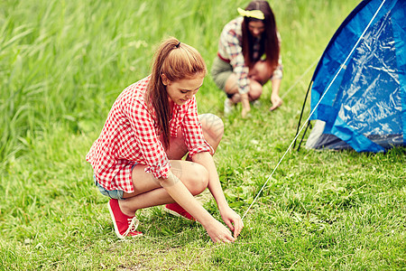 野营,旅游,远足人们的微笑的朋友户外搭帐篷图片