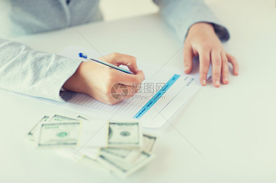 商业,金融,税收人的密切妇女的手与美元货币填写税单图片