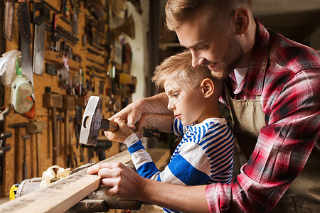 幸福的家庭,木工,木工人的父亲小儿子用锤击钉木板车间图片