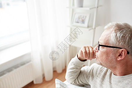 老,生活方式人们的亲密的老人戴着眼镜看着家里的窗户高清图片