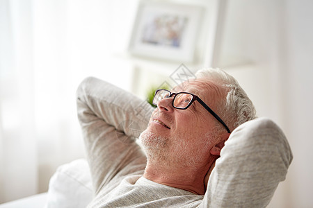 老,舒适人的微笑的老人戴着眼镜,家里沙发上放松图片