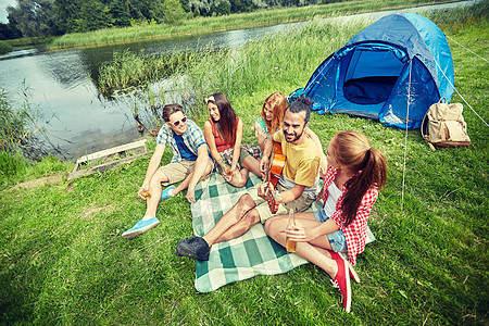 旅行,旅游,徒步旅行,野餐人们的群快乐的朋友带着帐篷饮料,露营时弹吉他图片