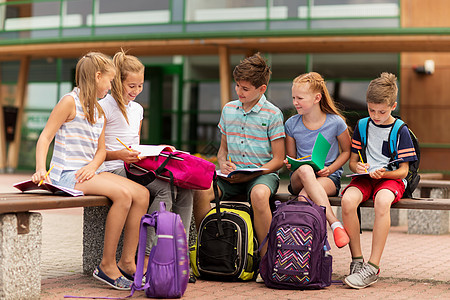 小学教育,友谊,童,沟通人的群快乐的小学生,背包笔记本坐户外长凳上图片