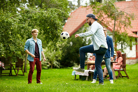 休闲,假日,人运动的快乐的朋友夏季花园聚会上踢足球图片