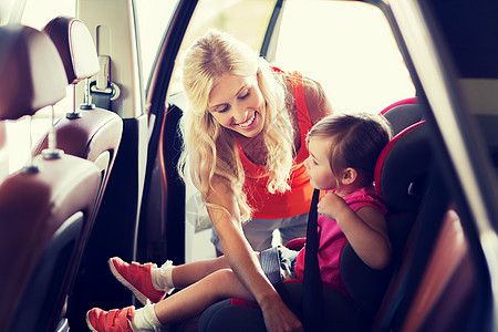 家庭,交通,安全,道路旅行人们的快乐的母亲系紧孩子的汽车安全带图片