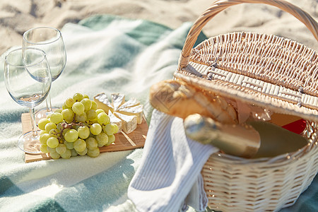 野餐布食物,假日庆祝野餐篮子与葡萄,酒杯,奶酪香槟瓶夏季海滩背景