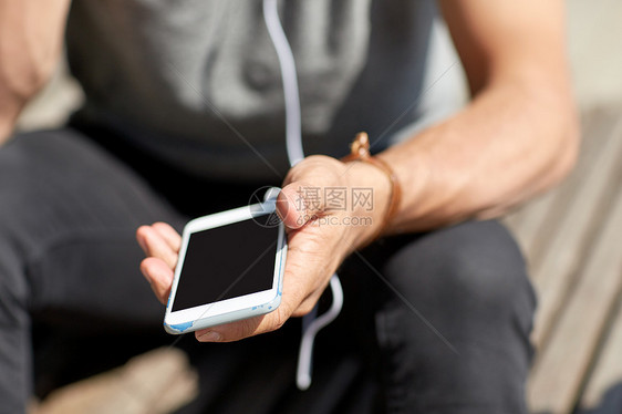 人技术近距离的人与耳机智能手机听音乐砖墙街上用智能手机耳机线男人图片