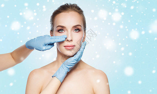 人,美容,整形手术美容外科医生美容师手触摸女人的脸蓝色的背景雪图片