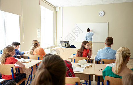 教育学校学教学人的教师站学生前,教室的白板上写些东西图片